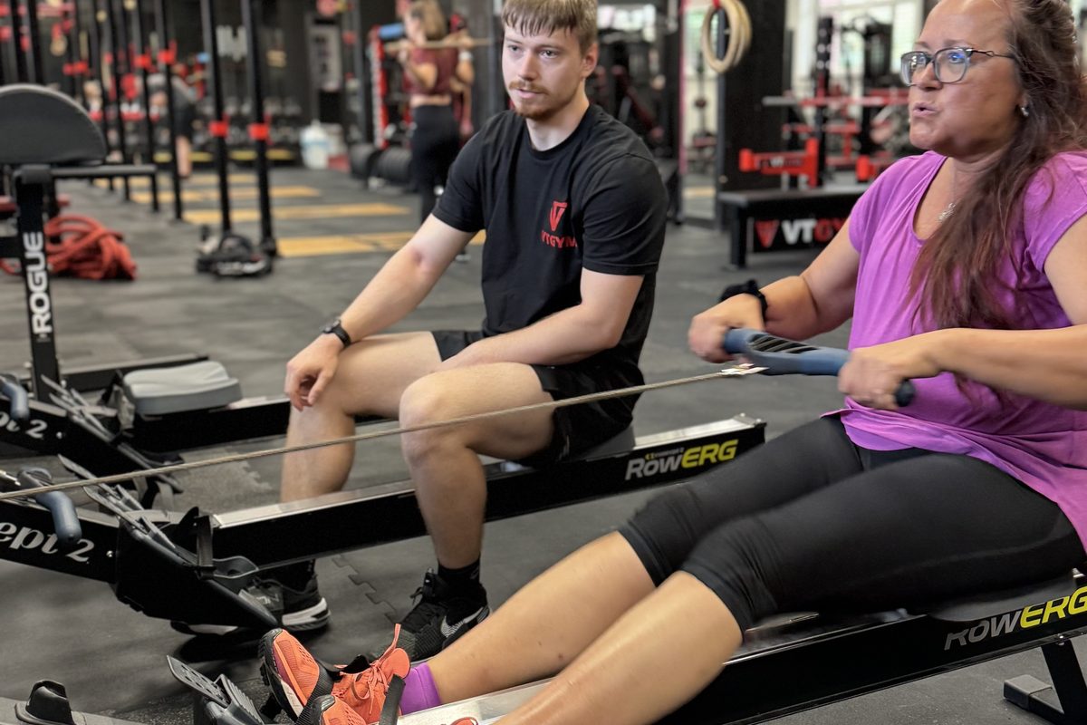 Trenér FitWay40 vede klientku na veslovacím trenažéru