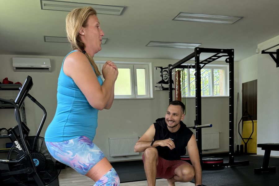 Klientka FitWay40 cvičí dřep pod vedením trenéra ve VT GYM