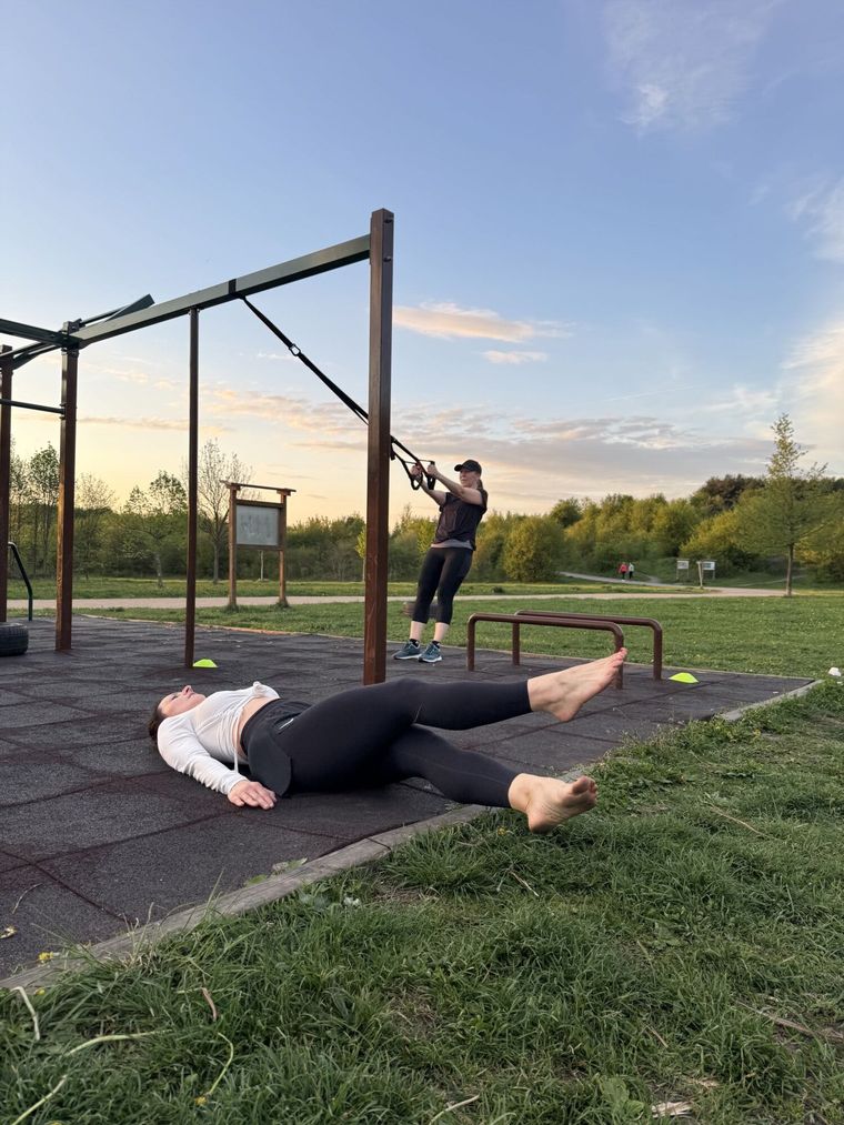 Klientka cvičí na TRX, druhá posiluje břicho na podložce