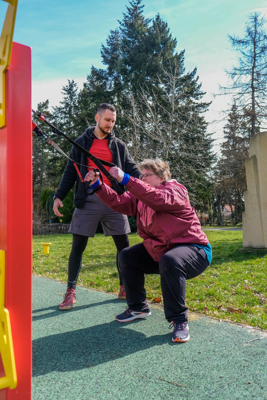Trenér hlídá klientce techniku při cviku na TRX